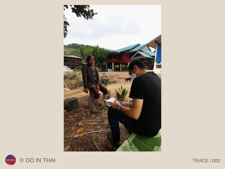 Two people talk outdoors near a building; one holds paper for notes.