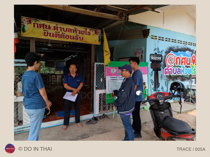 A small group talks at the entrance to a local learning centre; one person holds a sheet of paper.