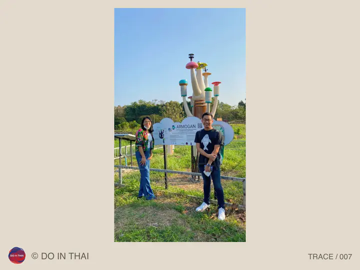 Two people stand beside an ARMOGAN sign and colourful instruments under a blue sky.