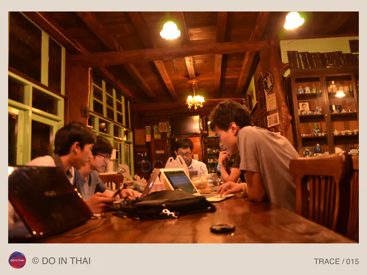 A team gathers with computers around a wooden table in a warmly lit room.