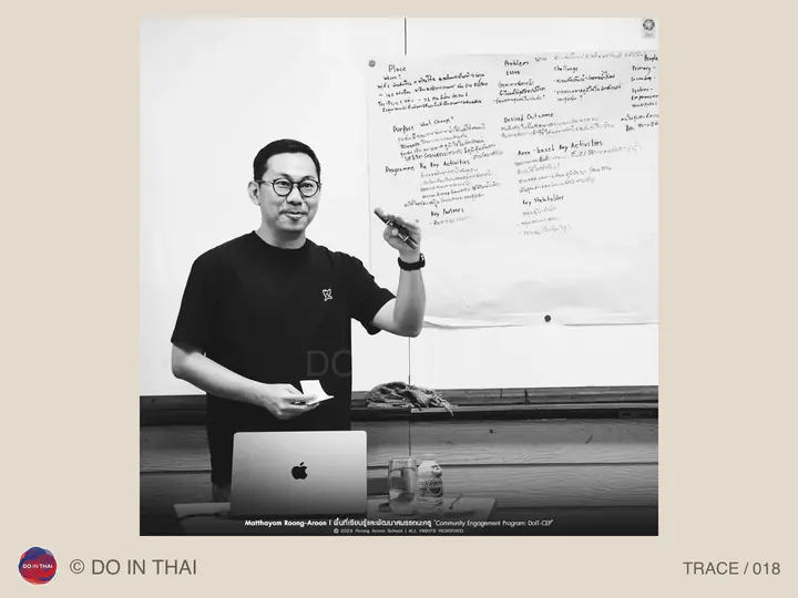 Black-and-white photograph of a speaker beside a laptop and handwritten planning sheets.
