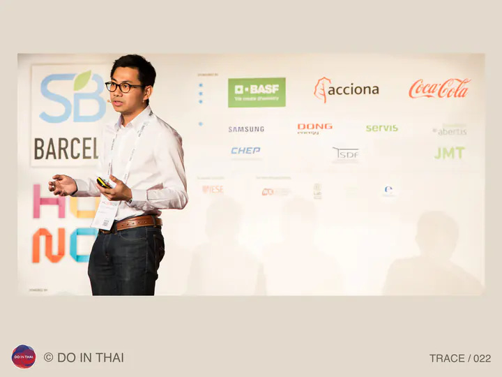 A speaker in a white shirt holds a presentation remote in front of a Sustainable Brands backdrop.