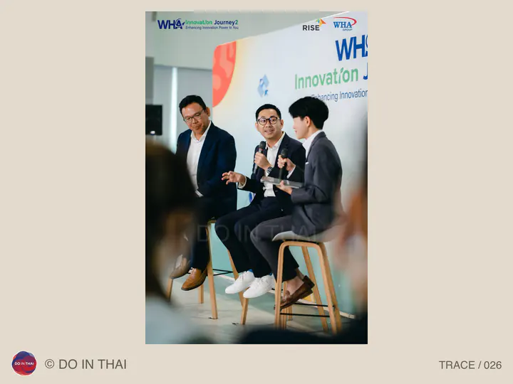Three panellists talk on tall chairs in front of an innovation event backdrop.