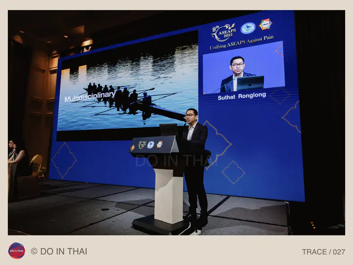 A presenter stands at a lectern beside a slide with a rowing boat and the word Multidisciplinary.