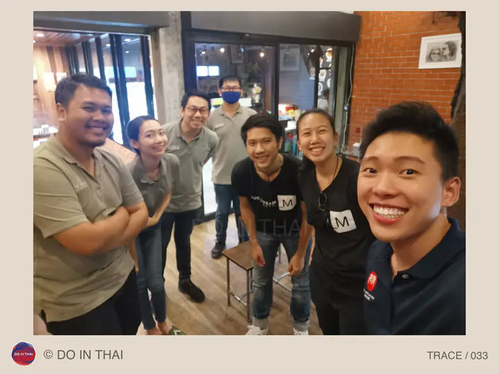 A smiling group takes a selfie inside a shop with brick walls and windows.