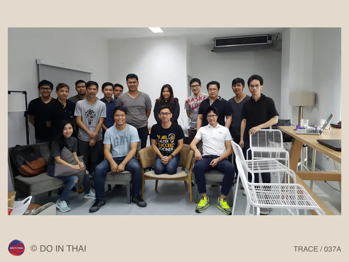 A group poses in two rows in a compact office, with seated people in front and others standing behind.