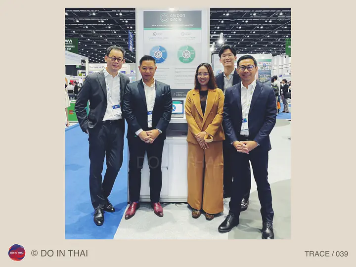 Five people pose beside a counter in a large exhibition hall.
