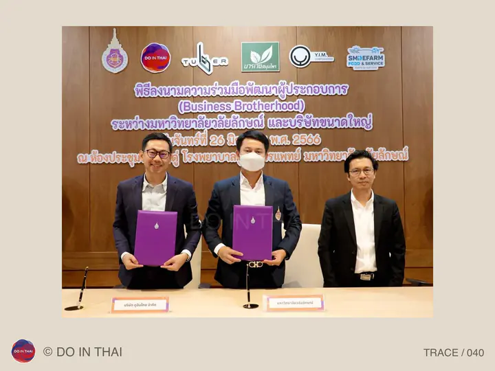 Three people pose at a collaboration event; two hold purple document folders.