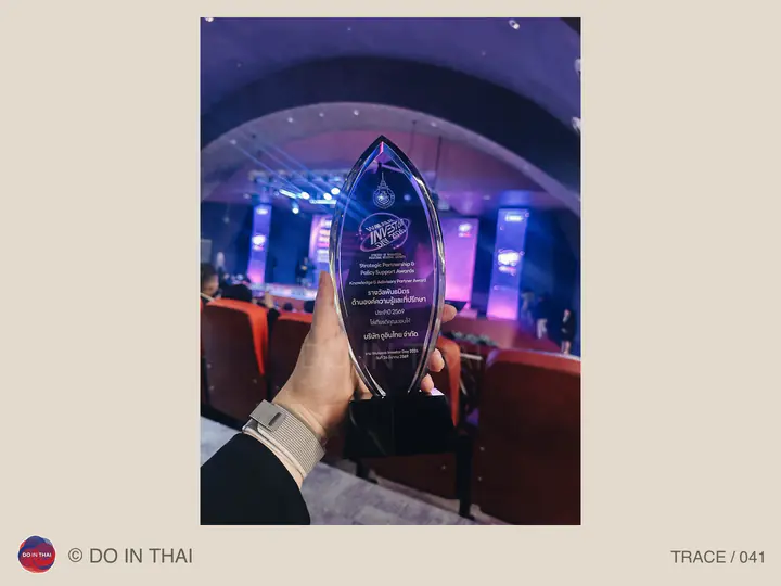 A hand holds a clear pointed award in an event hall lit with purple light.