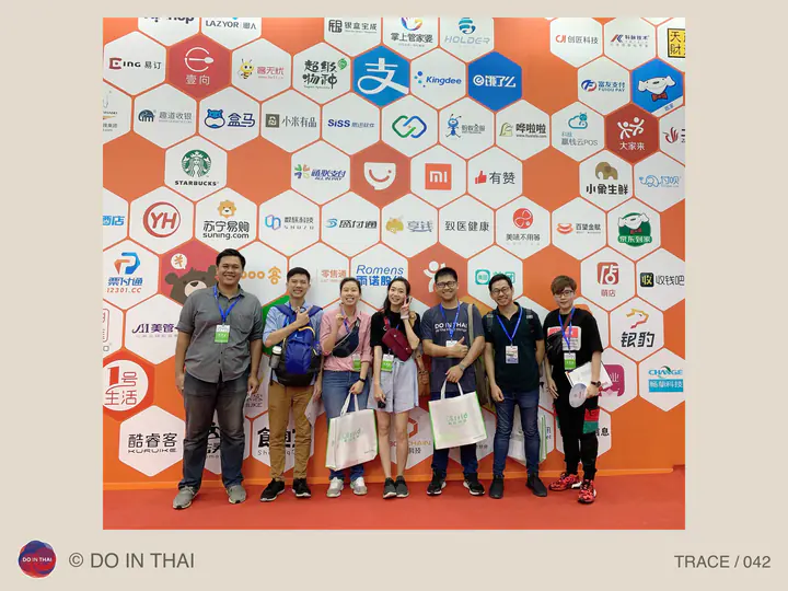 A group poses in front of a honeycomb-patterned wall filled with brand logos.