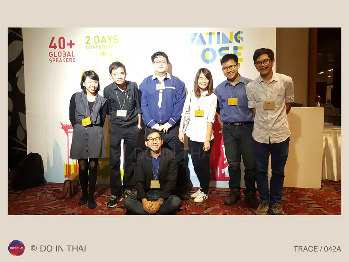 Seven people wearing event badges pose together in front of a brightly coloured conference backdrop.